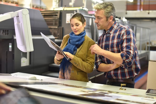 Man in printing house showing client printed documents - increase sales in manufacturing company