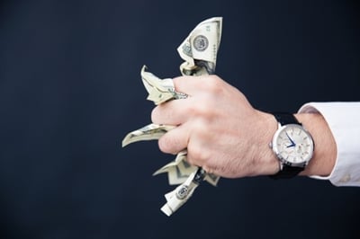 Closeup image of a businessman hand holding bills of US dollar in fist.jpeg