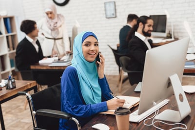 Smiling disabled Arabic woman on a computer