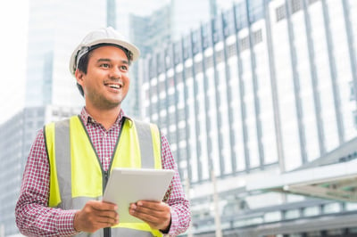 Smiling asian engineer with a construction helmet holding a tablet