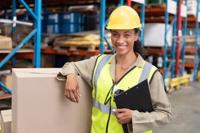 Smiling female industrial worker with a clipboard and hardhat