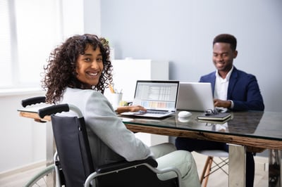 Smiling businesswoman in a wheelchair with a laptop