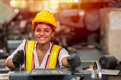 Smiling female industrial worker operating machinery