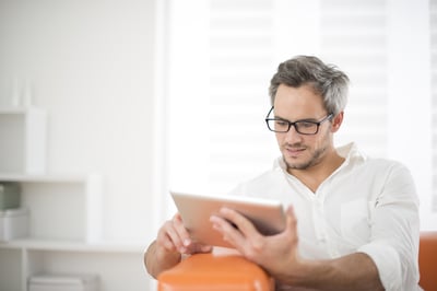 man reading manufacturing newsletters on tablet - manufacturing newsletters