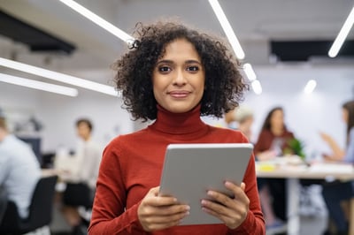 Smiling businesswoman of color with a tablet in a red sweater