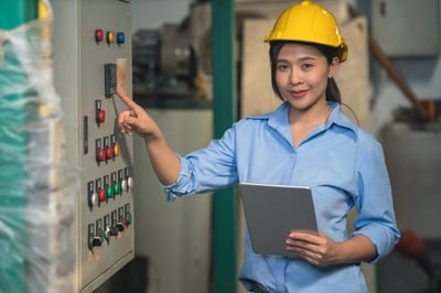 Smiling asian-american female industrial worker holding a tablet