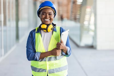 Smiling Black female engineer with a tablet and hi-vis vest