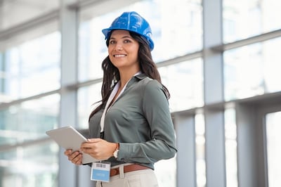 Smiling female engineer with a tablet and blue hard hat