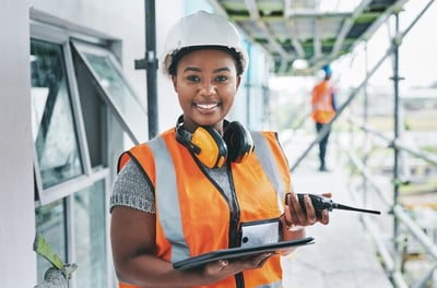 Smiling Black female engineer with an orange safety vest