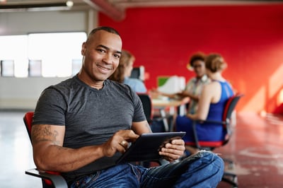 Smiling engineer with a tablet and red background