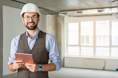 Smiling male procurer with a tablet and hard hat