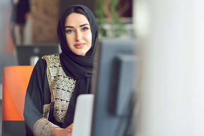 A woman with a headscarf sitting at a computer