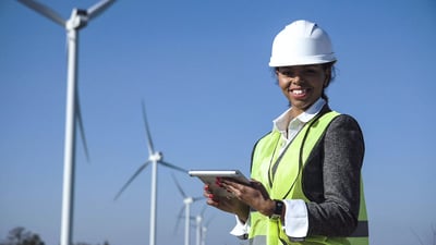 A smiling black female engineer with a construction helmet holding a tablet